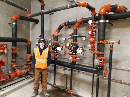 Picture of a student standing by pipes